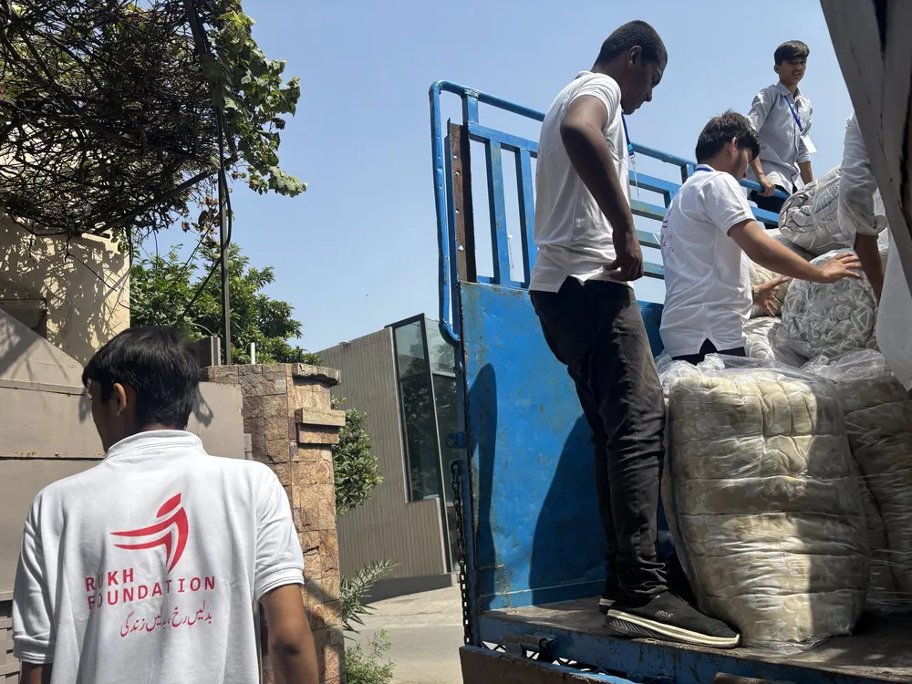 Volunteers and staff unloading large sacks from a truck during a relief distribution